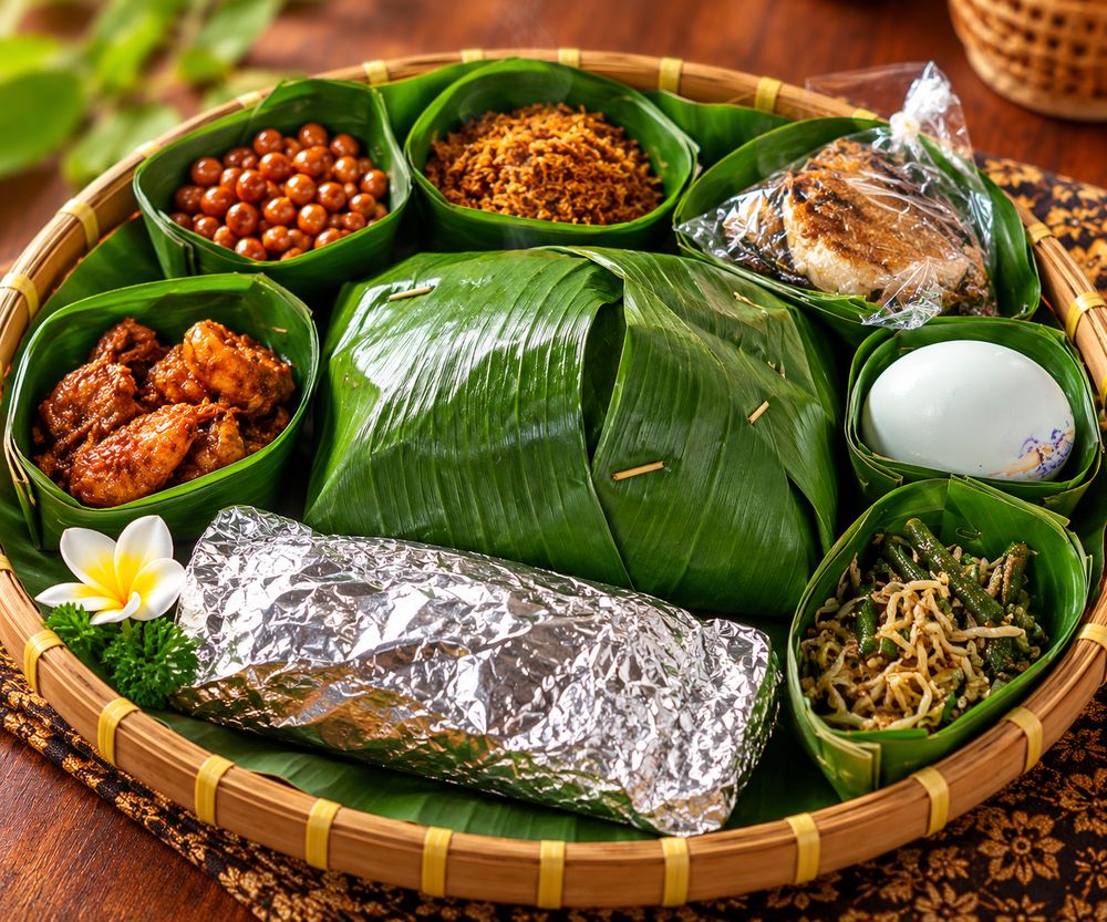 Rayunan Peranda dalam nyiru bambu berisi aneka hidangan dalam wadah daun pisang